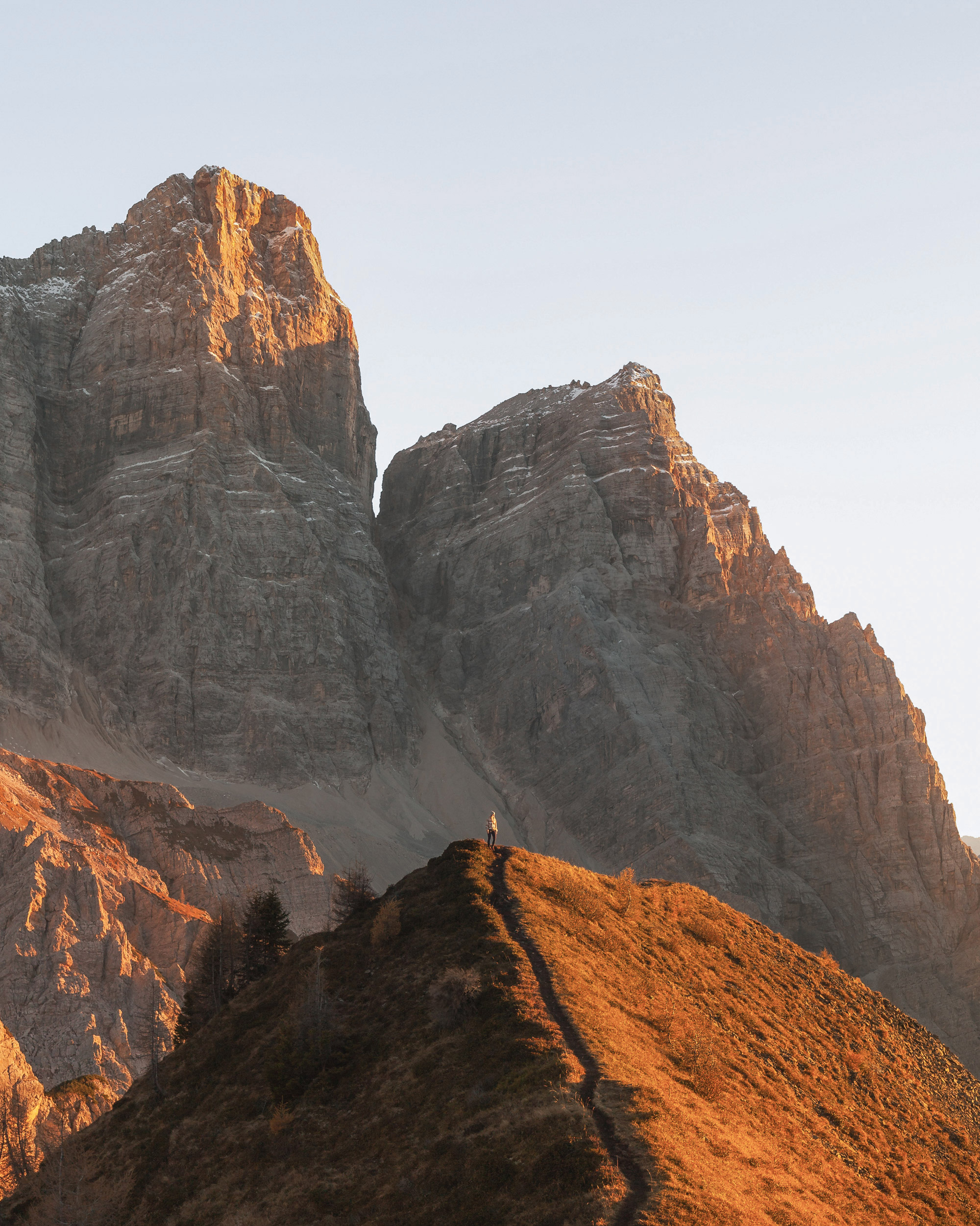 A narrow ridge leading to a small figure, with the massive Monte Pelmo peaks glowing in the background.