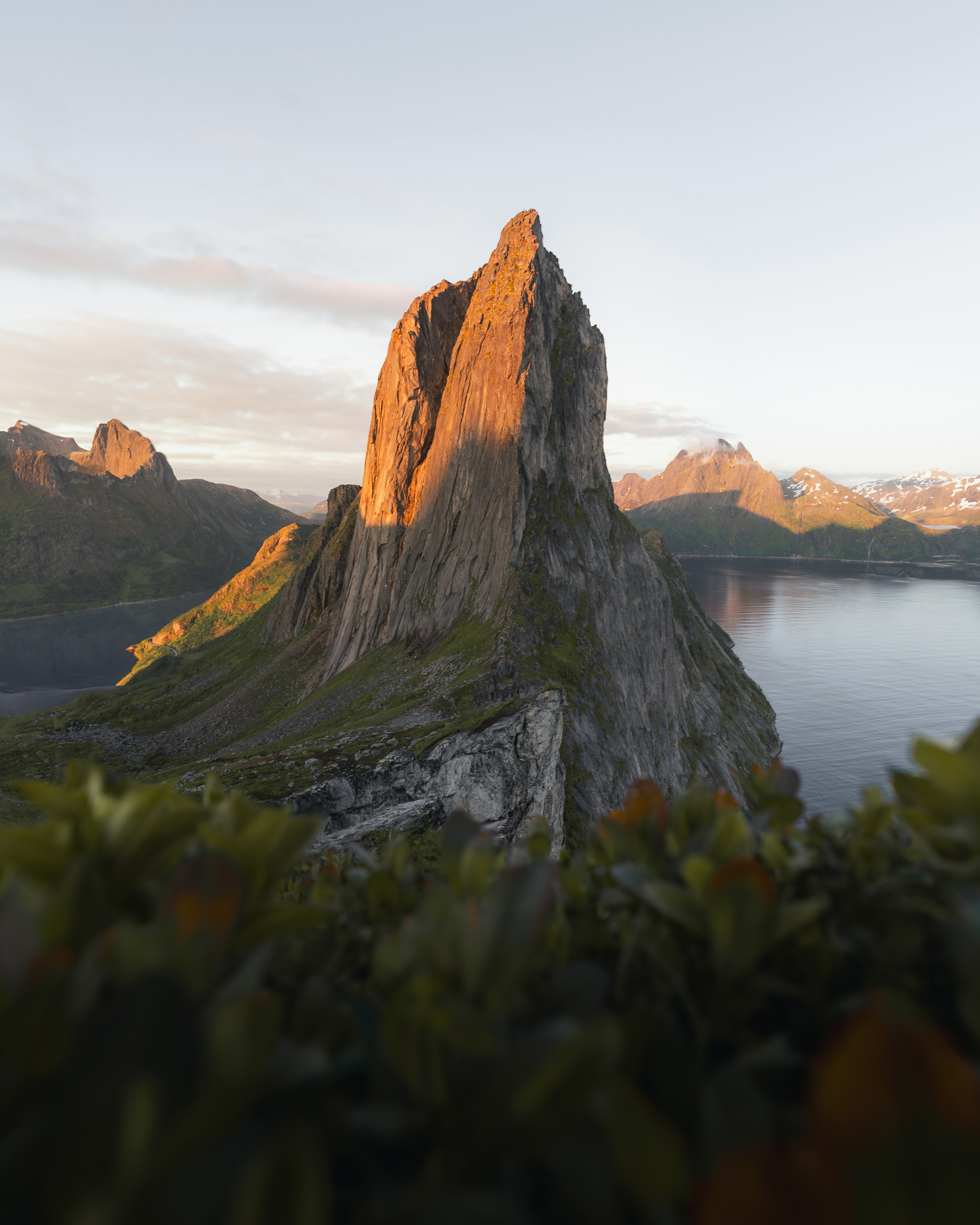 The image depicts a rocky mountain set against a picturesque backdrop of water. The scene captures the beauty of nature, with elements like the sky, clouds, and reflections in the lake during sunset or sunrise. It highlights the stunning landscape that combines rock formations with tranquil water.