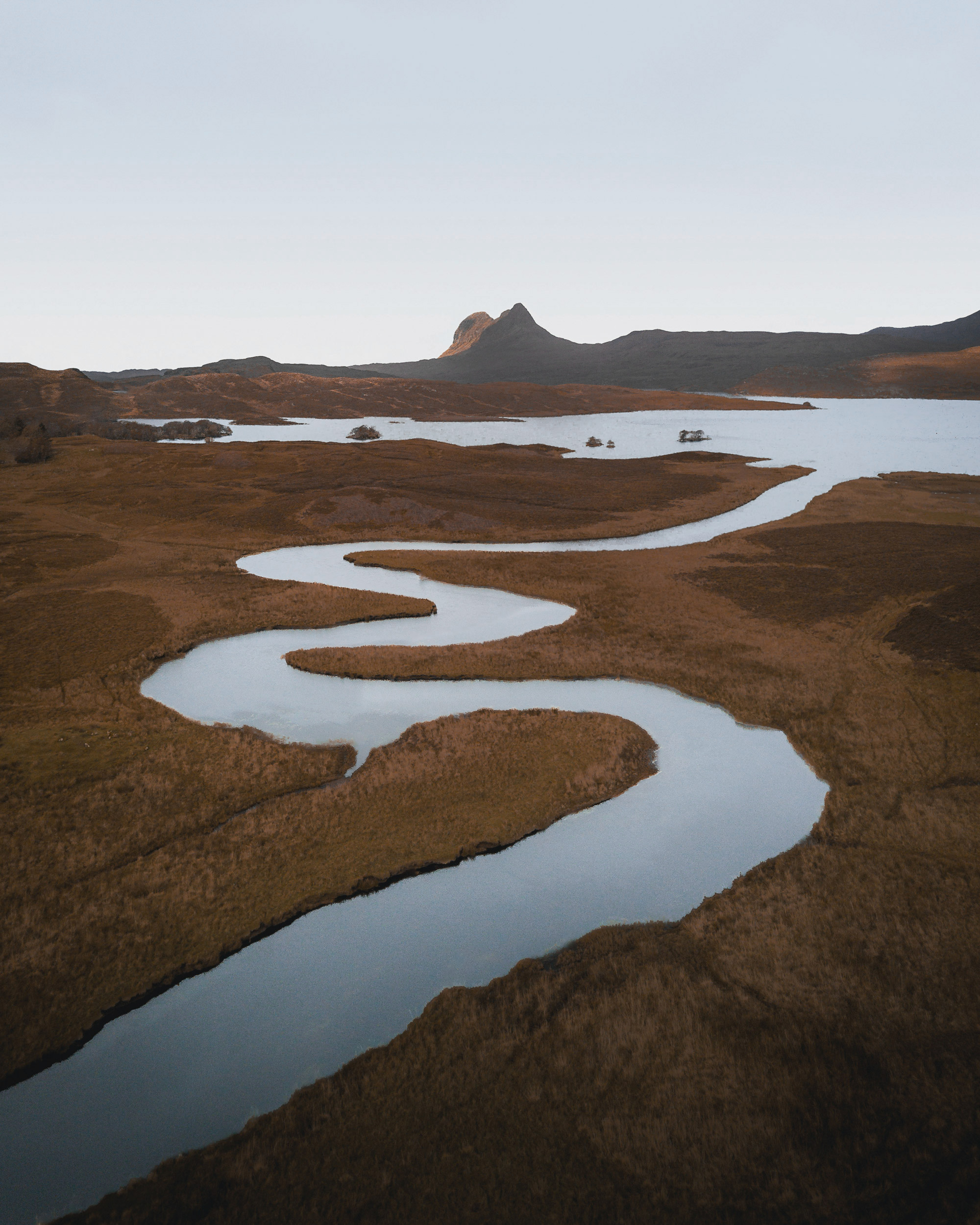 Serpentine river meanders through a landscape of muted browns and muted blues.
