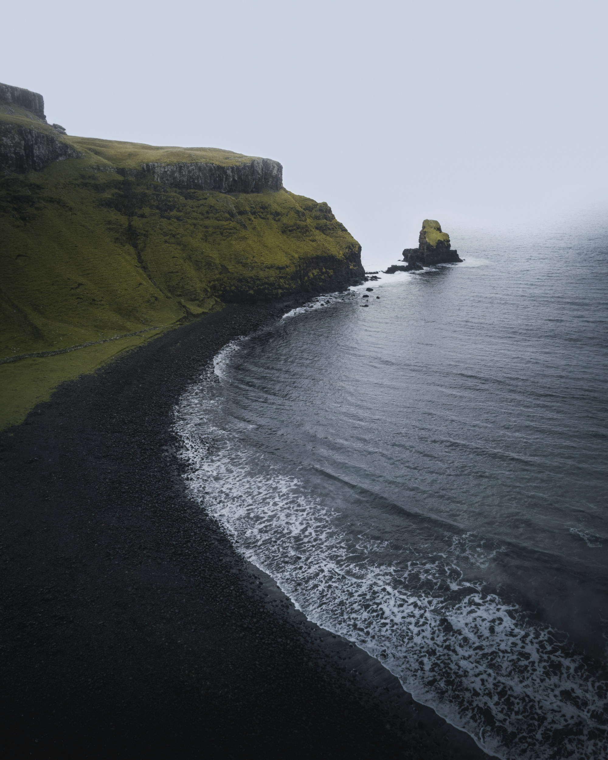The image features a rocky beach alongside a body of water. It showcases elements of nature, including coastal and oceanic landforms such as cliffs, waves, and possibly an island in the distance. The scene captures the beauty of the outdoors with its blend of land and sea.